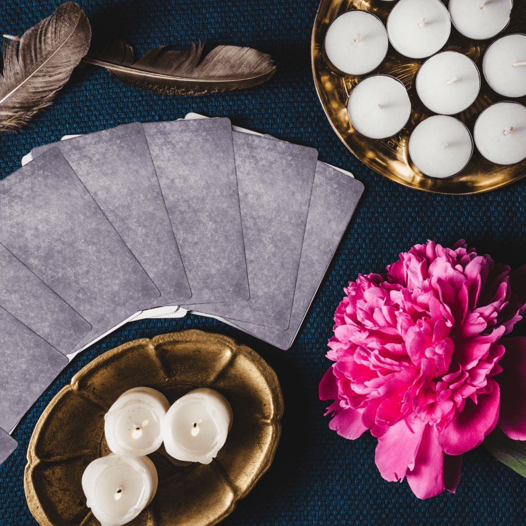 Oracle cards layed out on a table with a pink flower and white candles